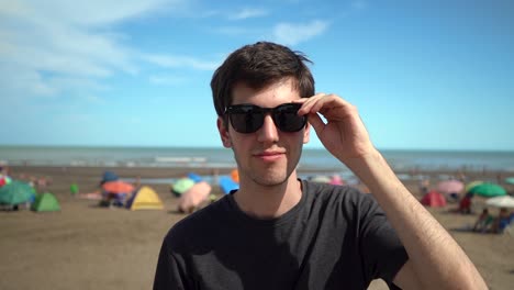 Junger-Gutaussehender-Mann-Setzt-Schwarze-Sonnenbrille-Auf-Und-Lächelt-Dann-In-Die-Kamera