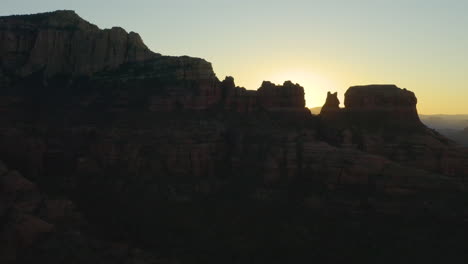 The-morning-sun-silhouettes-Bear-Mountain-and-surrounding-rock-formations-near-Sedona,-Arizona-at-dawn