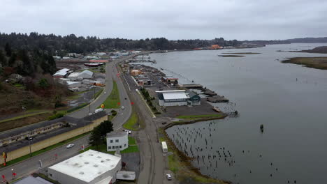 Vuelo-Aéreo-Hacia-Atrás-Sobre-La-Autopista-De-La-Costa-De-Oregon-Y-Antiguos-Edificios-Del-Muelle