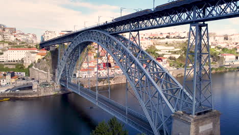 Aerial-view-of-Dom-Luís-I-Bridge-with-subway-passing-and-Porto-city,-drone-going-backward