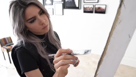 Artist-painting-with-high-concentration,-young-Latina-woman-in-close-up