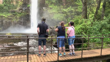 Touristenfamilien-In-Covid-Masken-Genießen-Den-Blick-Auf-Den-Wasserfall-Von-Der-Fußgängerbrücke-Aus