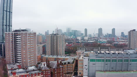 Descending-aerial-drone-shot-of-City-of-London-skyscrapers-cloudy-from-north-London