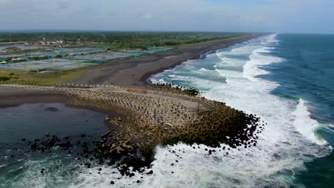 Grand-ocean-waves-hit-pier-tetrapod-breakwater,-Glagah-Beach,-Indonesia,-aerial