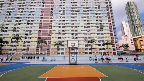 Gente-Detrás-De-La-Cancha-De-Baloncesto-Frente-Al-Edificio-Choi-Hung-Estate,-Hong-Kong,-Vista-Estática
