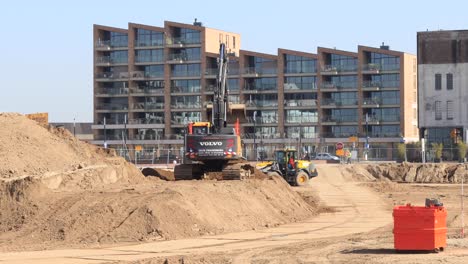Large-heavy-construction-work-machinery-with-bulldozer-and-digger-preparing-the-soil-of-a-plot-for-building-a-luxury-apartment-complex