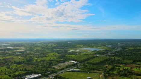 Hermosa-Vista-Aérea-Del-Cielo-Moviéndose-Y-Viendo-El-Campo-Pantanoso-Con-La-Carretera-Un-Día-Soleado-En-Khonkaen,-Tailandia