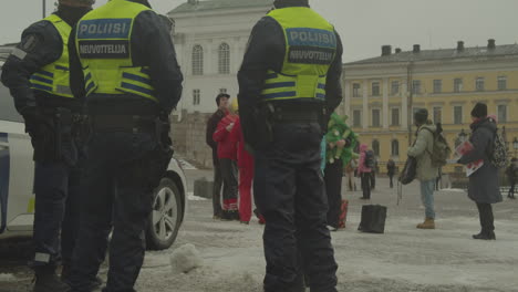 Policías-Parados-Al-Lado-Del-Coche-De-Policía-Cerca-De-Los-Manifestantes-En-La-Plaza-Del-Senado-Frente-A-Las-Escaleras-De-La-Catedral-De-Helsinki
