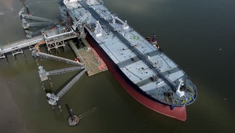 Crude-oil-tanker-ship-loading-at-refinery-harbour-terminal-aerial-birdseye-view-pull-back