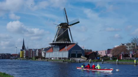People-Rowing-Past-Picturesque-Traditional-Wooden-Windmill-In-Utrecht,-Netherlands