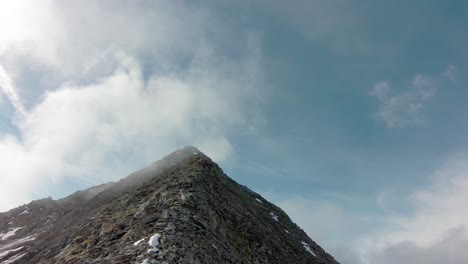 Drone-Aéreo-Fpv-Volando-Hasta-La-Cima-De-La-Montaña-Hacia-Las-Nubes-En-Los-Alpes-Suizos