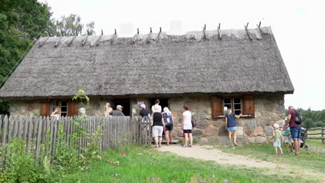 Menschenmenge-Steht-Vor-Einem-Alten-Haus-Aus-Steinen-Und-Strohdach-Und-Wartet-Darauf,-Einen-Blick-Ins-Innere-Zu-Werfen