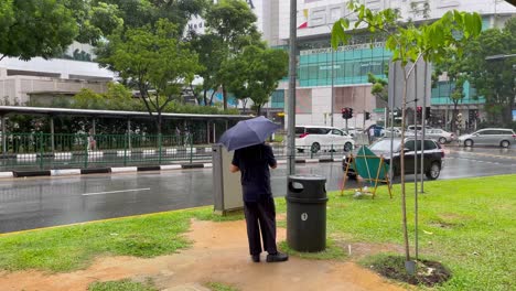 Man-taking-a-smoking-break-on-rainy-day,-Novena,-Singapore