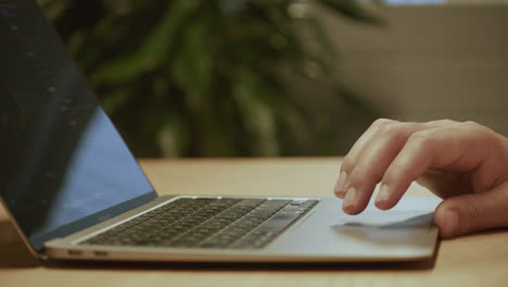 Side-view-of-a-man-standing-at-a-desk-working-on-a-MacBook-Air-M1