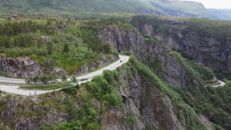 Road-curving-around-dangerous-edge-of-cliff-in-dramatic-landscape-Hardangervidda-Norway---Aerial
