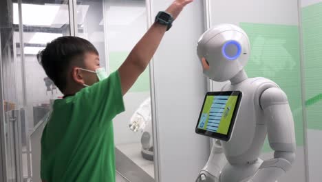 Ein-Junger-Besucher-Interagiert-Mit-Einem-Roboter,-Während-Er-Während-Der-„Roboter“-Ausstellung-Im-Hong-Kong-Science-Museum-In-Hongkong-Dessen-Kopf-Berührt