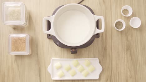 Köchin-Gießt-Milch-In-Einen-Kochtopf-Auf-Einem-Elektroherd,-Draufsicht-Statisch