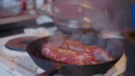 Fumar-Carne-Roja-En-Una-Sartén-De-Hierro-Fundido-En-La-Antigua-Cocina-De-Campo,-Tiro-Medio-De-Mano