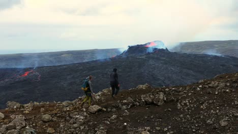 Fagradalsfjall-mountain,-GrindavÃ­k,-Reykjanes-peninsula,-Southwest-Iceland-with-people-hiking-to-the-eruption-site---aerial-drone-shot