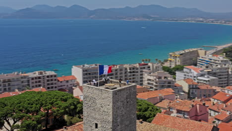 Cannes-France-Aerial-v35-low-level-drone-flying-around-chateau-de-la-castre,-medieval-watchtower-capturing-surrounded-cityscape-and-old-port---July-2021
