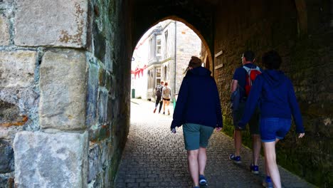 Visiting-tourist-groups-walking-through-medieval-stone-town-tunnel-archway-alley
