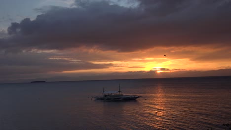 Sonnenuntergang-über-Dem-Meer-Auf-Den-Philippinen-Mit-Einer-Kleinen-Insel-Im-Hintergrund-Und-Einem-Traditionellen-Philippinischen-Boot-Im-Vordergrund