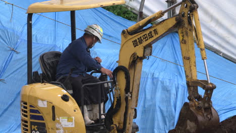 Trabajador-De-Cuello-Azul-Que-Opera-Una-Excavadora-En-El-Sitio-De-Construcción-En-Un-Clima-Lluvioso