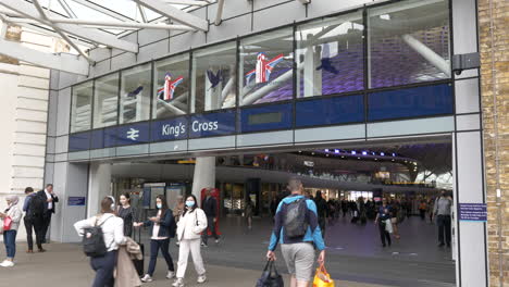 Kings-Cross-Station-Entrance,-commuters-walking-in-and-out,-some-wearing-face-masks