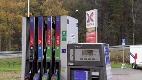 Handheld-shot-petrol-station-pump-terminal,-cars-driving-at-background,-Gothenburg---Sweden