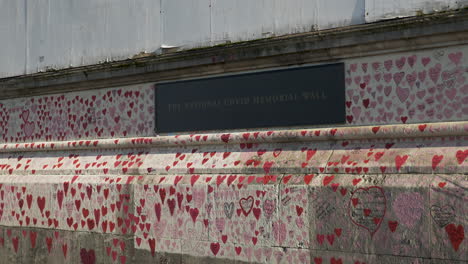 La-Placa-Que-Conmemora-El-Muro-Conmemorativo-Nacional-Del-Covid,-El-Muro-Cubierto-De-Miles-De-Corazones-Rosas-Dibujados-A-Mano-Que-Sirven-Como-Recuerdo-De-Aquellos-Que-Han-Muerto-Debido-A-La-Pandemia,-Londres,-Inglaterra