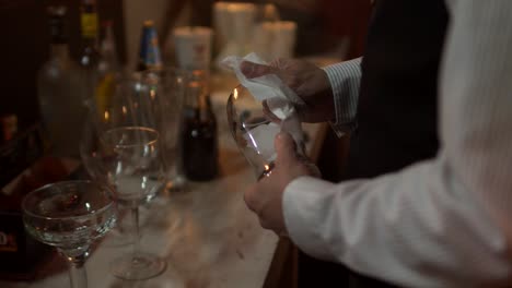 Waiter-in-a-bar-cleaning-the-glass-glasses-during-a-party,-unrecognizable-person-side-view-close-up