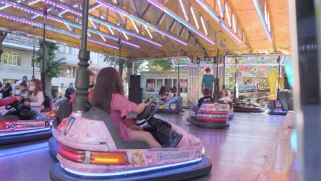 Los-Niños-Enmascarados-Se-Divierten-Montando-Autos-Chocadores-En-El-Parque-De-Diversiones.