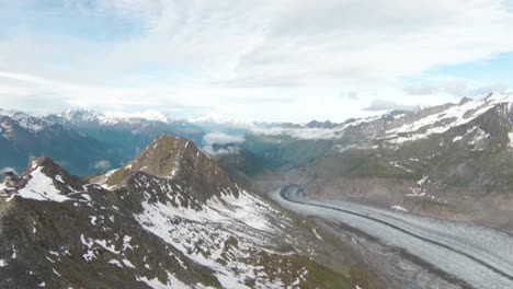 Aerial-drone-fly-by-over-mountain-top-with-FPV-drone-close-to-aletsch-glacier,-Switzerland-with-3-people-standing-on-mountain-top