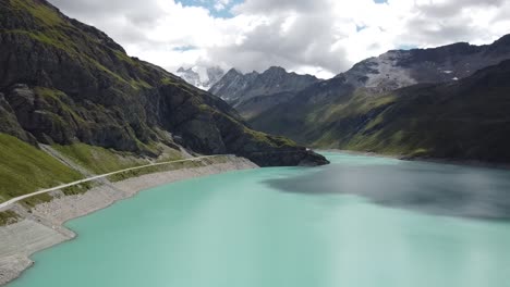 the-beautifully-shining-lac-de-moiry-from-a-bird's-eye-view,-beautifully-situated-in-the-middle-of-the-Swiss-Alps-in-the-canton-of-valais