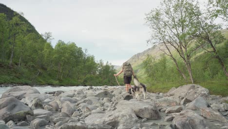 Excursionista-Noruego-Está-Haciendo-Senderismo-Con-Un-Perro-Que-Pasa-Por-Un-Río-Rocoso-En-La-Montaña-Del-Bosque-De-Lyngsdalen-En-Noruega