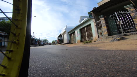 Low-angle-shot-of-motor-bike-wheel-riding-fast-on-small-town-road-in-Vietnam