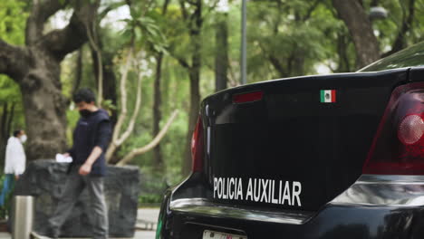 A-police-car-in-Mexico-City-with-pedestrians-wearing-masks-walking-past-in-the-background