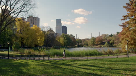 Woman-In-Pink-Pants-Walks-Dog-Near-Harlem-Meer-In-Central-Park,-New-York-City,-U