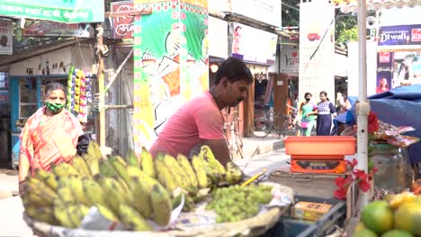 Poor-Indian-hawker-selling-fruits-on-street-at-daytime,-working-class,-people-walking-by