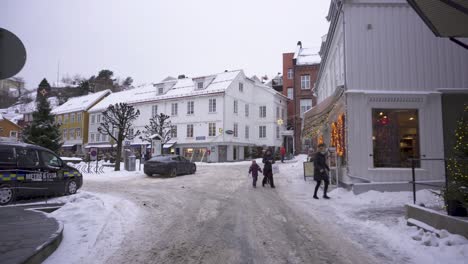 Tourists-Running-Towards-Charming-Winter-Town-Shops-In-Kragero,-Norway---wide-shot