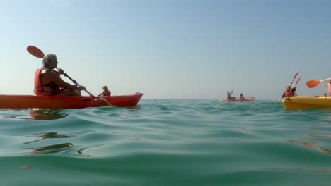 Low-angle-sea-level-view-of-many-tourists-on-holiday-paddling-in-kayak-on-hot-summer-day