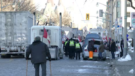 Policía-Cruzando-Una-Calle-Bloqueada-Entre-Residentes-Y-Camiones-En-Huelga-Contra-Las-Medidas-Gubernamentales-Sobre-Covid19---Ottawa,-Ontario,-Canadá