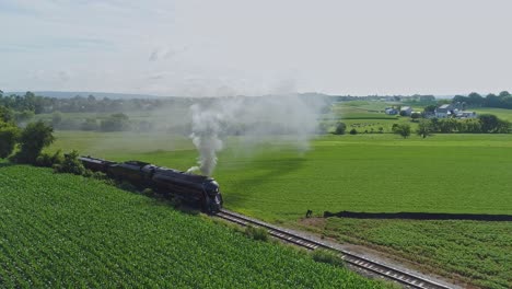 Paisaje-Aéreo-De-Tierras-De-Cultivo-Y-Un-Motor-De-Vapor-Antiguo-Pasa-A-Través-De-Los-Campos-De-Maíz-En-Una-Mañana-De-Verano-Temprano