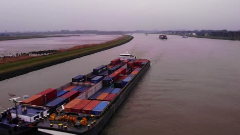 Aerial-Flying-Over-Maas-Cargo-Ship-Paired-With-Another-Carrying-Containers-On-River-Noord-On-Cloudy-Afternoon