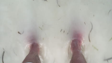 Feet-standing-on-white-sand-beach,-washed-by-sea-waves,-close-up