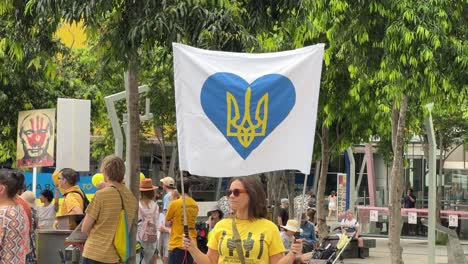 Pacifista-Amante-De-La-Paz,-Mujer-En-La-Plaza-De-Brisbane-Sosteniendo-Una-Pancarta-Con-El-Escudo-De-Armas-En-Forma-De-Corazón-De-Ucrania-Durante-La-Manifestación-Pidiendo-La-Paz-A-Medida-Que-Aumenta-La-Tensión-Entre-Rusia-Y-Ucrania
