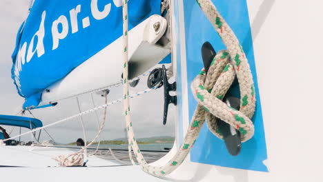 Sailboat-closeup-of-sheet-attached-to-mast,-boom-and-sea-scenery-on-background,-handheld