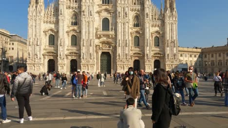 Tilt-up-of-tourist-taking-photo-at-woman-posing-in-Duomo-di-Milano-or-Milan-Cathedral-square-in-Italy