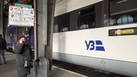 Ein-Zug-Mit-Flüchtlingen,-Die-Vor-Der-Russischen-Invasion-Fliehen,-Fährt-Von-Einem-Bahnhof-Ab-Und-Fährt-An-Einem-Handgefertigten-Schild-Vorbei,-Auf-Dem-Steht:-„Ukrainer-Kommen-Zurück-In-Die-Ukraine,-Deine-Eltern-Warten-Auf-Dich.“