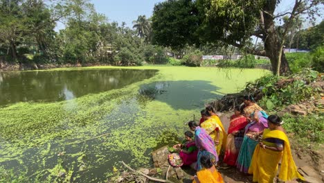 Frau-Führt-Rituale-In-Der-Nähe-Eines-Grünen-Teichs-In-Einem-Vorort-In-Westbengalen-Durch,-Um-Die-Reiszeremonie-Des-Kindes-Im-Bengalischen-Stil-Zu-Feiern